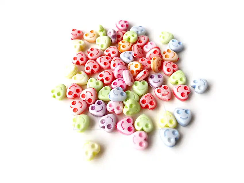 CUENTAS DE PLASTICO CORAZON CON CARITAS 8MM X 125GR 8950.M77